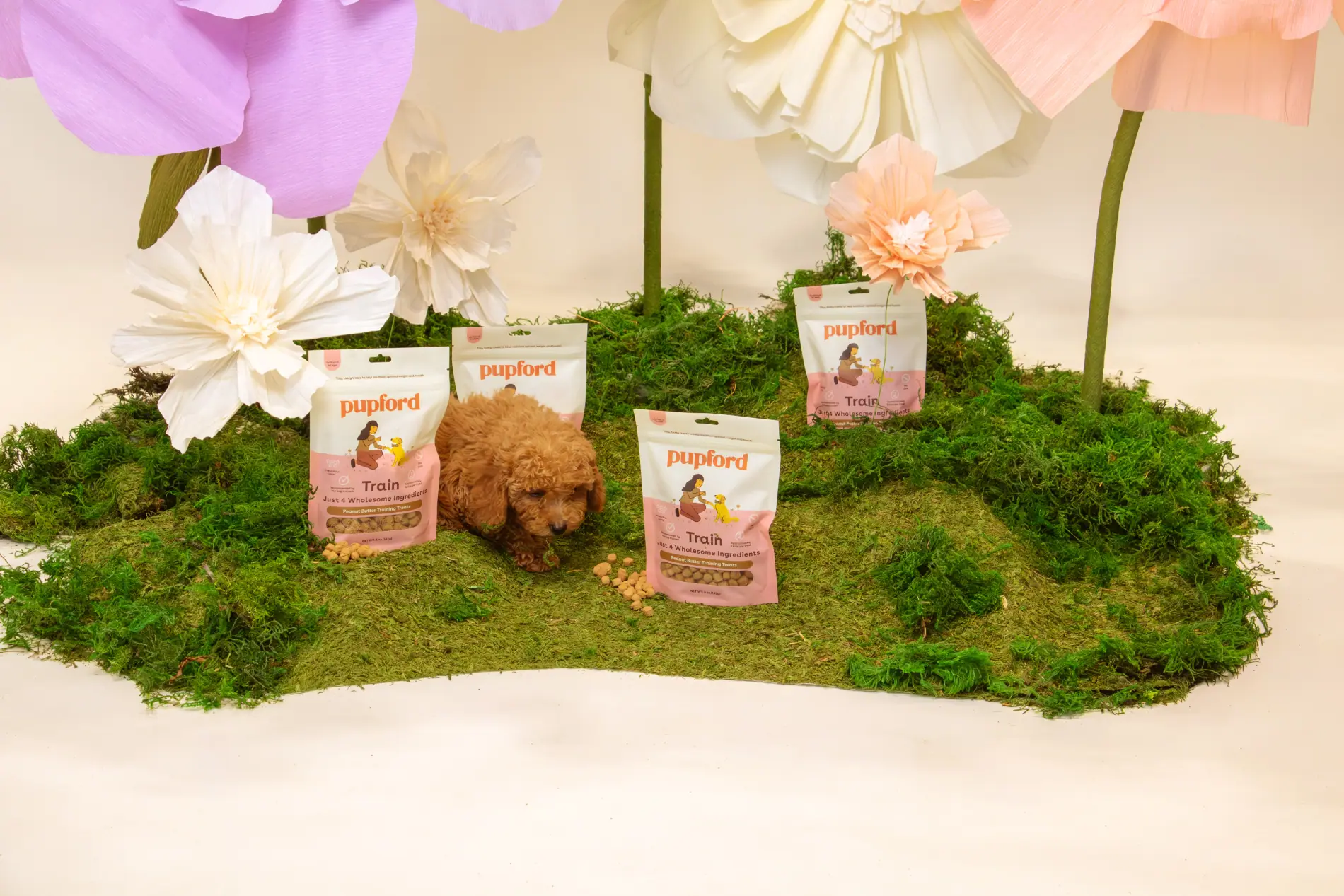 Studio set of oversized paper flowers and moss with Pupford Train bags arranged across it
