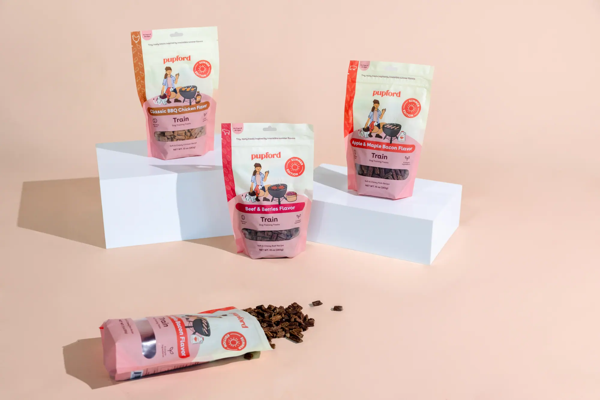 Three Pupford Train treat bags arranged on blocks with treats scattered on a peach background